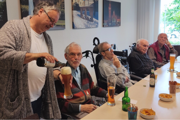 Krefeld: Mitarbeiter serviert Bewohnern Getränke.
