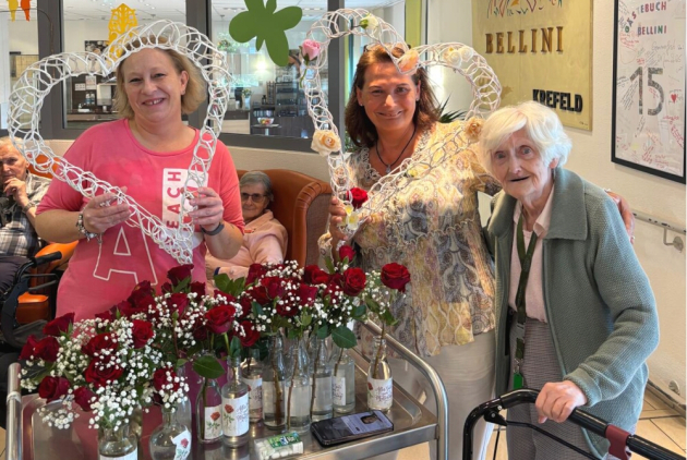 Krefeld: Mitarbeiterinnen und Bewohnerin hinter Wagen mit Rosen.