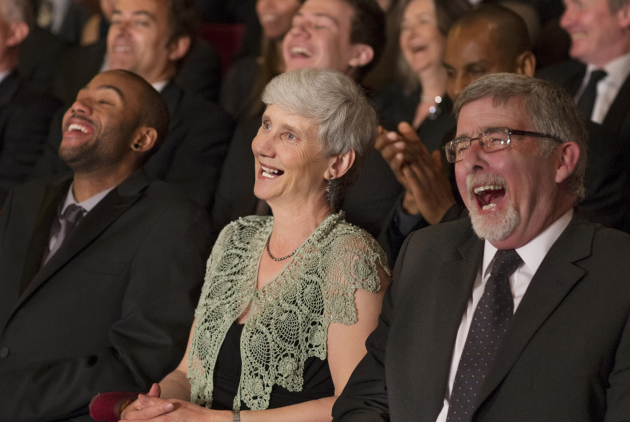 Publikum mit SeniorInnen lacht bei einer Theateraufführung.