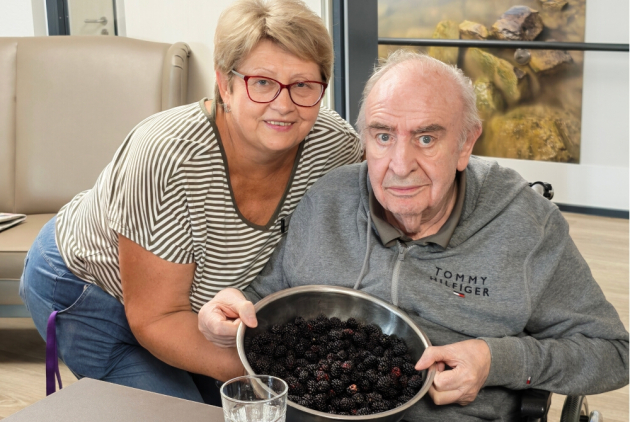 Neuwied: Mitarbeiterin neben Bewohner mit Schüssel voll Brombeeren.