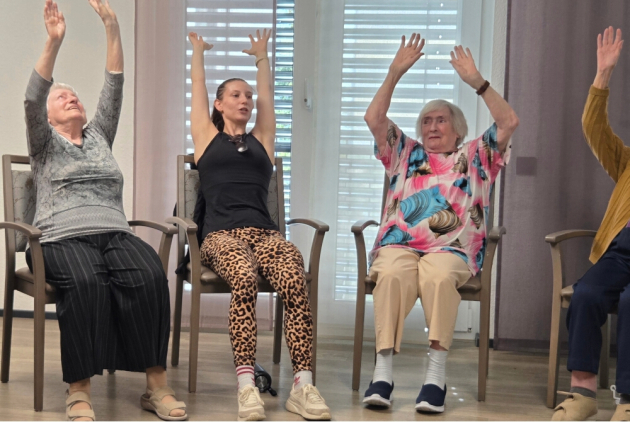 Neuwied: Bewohnerinnen und Yogalehrerin strecken im Sitzen Arme in die Höhe.