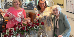 Krefeld: Mitarbeiterinnen und Bewohnerin hinter Wagen mit Rosen.