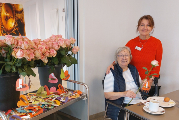 Dorsten: Bewohnerin und Mitarbeiterin neben Wagen mit Rosen und Herzen.