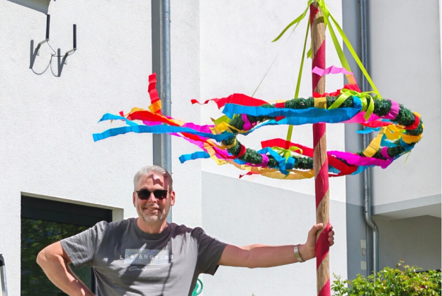 Neuwied: Mitarbeiter neben geschmücktem Maibaum.
