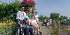 Neuwied: BewohnerInnen und MitarbeiterInnen vor Blumensträuchern zwischen Schrebergärten.